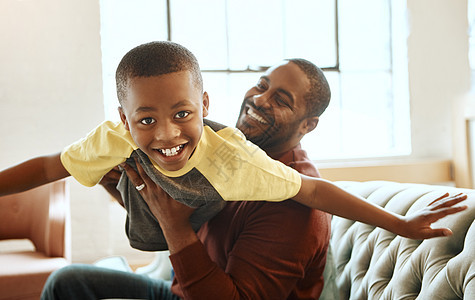 家人 肖像和父亲带着儿子坐在沙发上 在家里玩飞机 玩游戏和建立亲密关系 爱 父母和孩子在客厅玩耍 微笑和放松 而男孩则享受飞行 图片