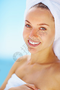 年轻漂亮的女性穿着浴巾微笑着洗完澡 沐浴后裹着毛巾微笑着的年轻女子的画像图片