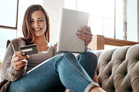 女性在沙发上进行支付 数字平板电脑和信用卡 在家中进行电子商务和在线购物 女孩 在线购物 放松地检查借记卡以在客厅购买或订阅图片