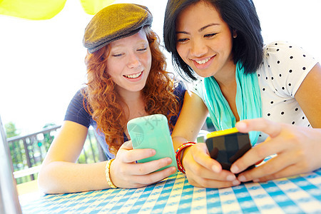 对比设备 两个少女坐在外边 在手机上发短信的年轻女孩图片