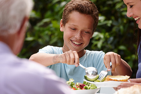一个小男孩在外面和家人一起吃午饭 外出吃沙拉图片