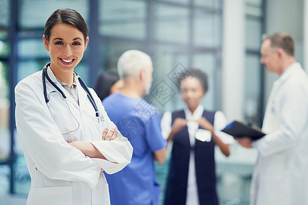 我的团队会照顾好你 一位年轻女医生的画像站在医院里 背景是同事图片