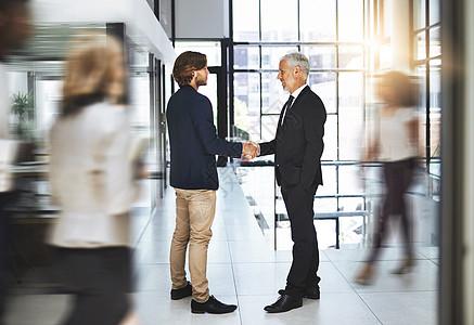 两位商务人士在繁忙的办公室握手 他们将同心协力 共同走向成功之路图片