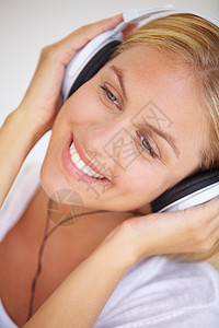 音乐使我微笑 一个美丽的年轻女人用耳机听音乐的音响 她很可爱图片