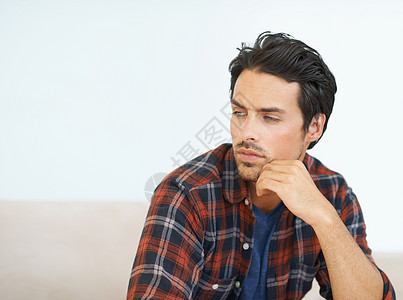 一位坐在沙发上 手牵手的美丽年轻男子躺在下巴上 脸上充满了思念和思考 (掌声)图片