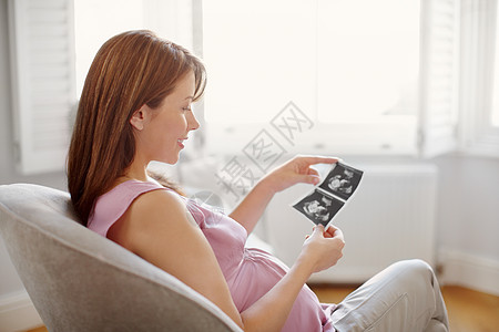 展望未来 漂亮的年轻女人坐在家里看着她的婴儿超声检查图片
