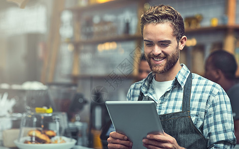 利用现代技术紧跟小型企业趋势 一个年轻人在他工作的商店里使用数字平板电脑图片
