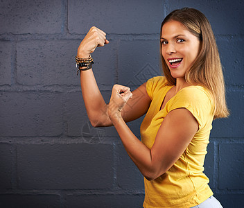 剪裁的年轻女子拳头对着砖墙背景的肖像画 你真的想用这些肌肉来对付她吗?图片