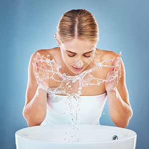 在蓝色背景工作室的水槽或盆地美容护肤中 女人 水或洗脸 用于卫生维护 保健或健康的美容模型 带水溅的湿式和面部清洁图片