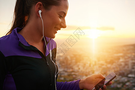 一位年轻女子在跑步时 在手机上听音乐 她的心声很振奋图片