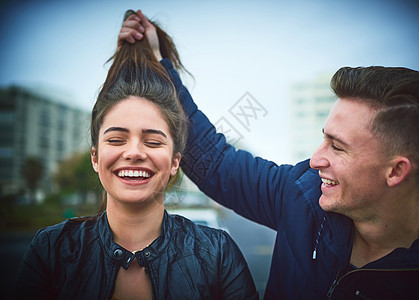 和这两个人玩得开心又游戏 一个年轻人在户外耍花样拉他的女朋友的头发图片