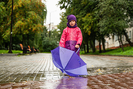 雨中带着伞子的小孩走在雨中 小男孩 户外有伞子雨衣公园飞溅靴子乐趣婴儿花园舞蹈水坑雨靴图片