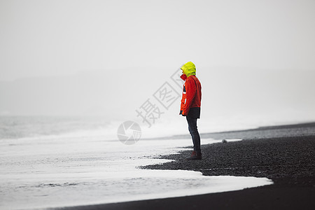 穿着红色夹克的人站在雷尼斯法哈拉海滩上图片