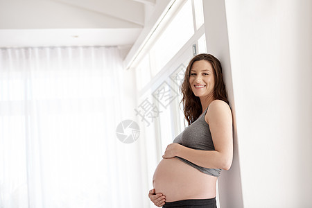 每次怀孕都是不同的 一个年轻孕妇站在家中的画像被刻上印记了图片