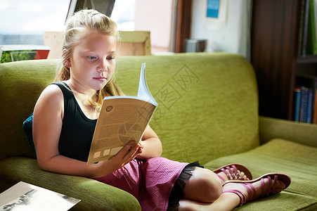 在沙发上、看书有个可爱的金发女孩在沙发上放轻松 写着一本好书背景