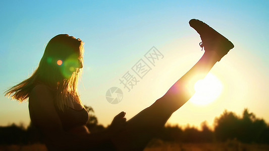 图 一个美丽 运动的女孩的轮廓 长着金发 在夏天做运动 拳击 飞腿 在日落时跳跃 在蓝天 阳光下跳跃活动放松跳绳身体潮人手臂公园图片