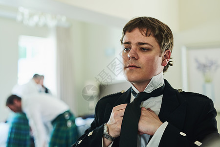 我必须确保我今天看起来最好 一个自信的年轻人一边照镜子一边折叠领带 为婚礼做准备图片
