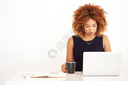 现代女商务人士的现代技术 一个年轻女商务人士在她的办公桌上用笔记本电脑工作图片