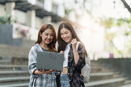 有朋友的美丽的年轻亚裔女大学生在户外 在大学校园工作的大学生女性笔记本技术学校朋友们学习班级电脑阅读男性图片