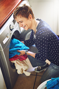 你进去吧 一个快乐的年轻女人 在家里从洗衣机里洗了衣服图片