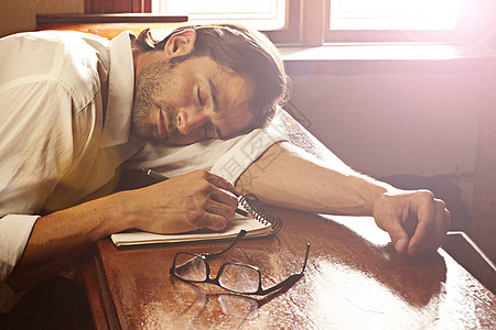 一个英俊的年轻人睡在他的笔记本上 在酒吧里睡觉了眼睛小憩黑发环境头发男人棕色成人写作记者图片