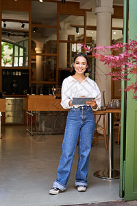 站在咖啡厅入口前的女服务员 向餐厅里带平板电脑的宾客邀请一对餐饮客人店铺企业家职员女孩成功互联网商务横幅人士咖啡图片