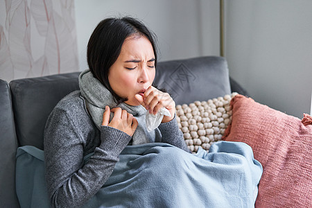 亚洲女性咳嗽 感觉不舒服 坐在寒冷的公寓里带着疤痕的毯子下 今年冬天节省取暖费 感染流感图片
