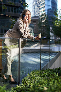 穿着米色西装的时髦女办公室女职员 在街上站在外面喝清晨咖啡时用手机说话公司职场面试套装女性售货员工作自信女士雇主图片