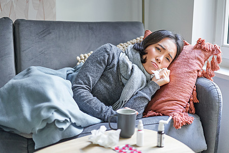 生病的妇女躺在沙发上 感寒 年轻女孩因为公寓的供暖问题而冷冻 认为生活费用高的概念成人药品长椅症状房子组织发烧温度流感病人图片