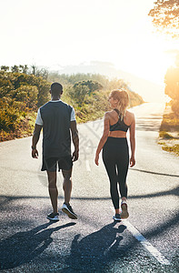 在自然健身房锻炼 一对健壮的年轻夫妇在户外跑步时慢下来散步图片