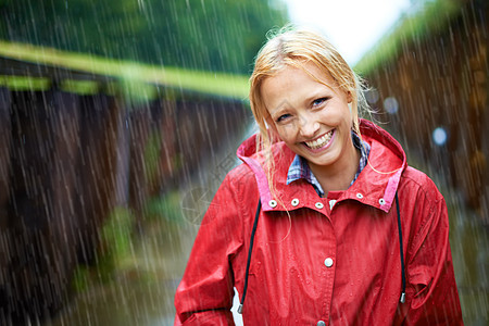 雨下得真好 美丽的金发美女 在乡间公路的户外雨中穿着红色雨衣 (笑声)图片