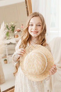 长发的美少女在镜子前戴上草帽 对金发女郎的自以为是的感觉帽子身体验收裙子女孩女士幸福配件洞察力达人图片