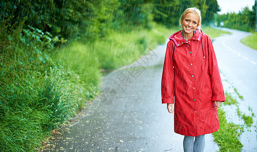 雨天走在乡间小路上 美丽的年轻金发女人在乡间小路上的户外雨中穿着一件红色雨衣图片