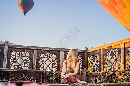 在土耳其卡帕多细亚看热气球的女游客 土耳其概念中的快乐旅行 山顶上的女人享受美妙的景色旅游裙子岩石假期女孩空气阳光气球家庭日出图片