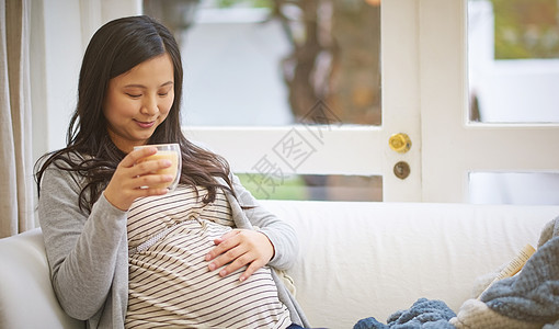 一个有吸引力的年轻孕妇 喝着冰咖啡 同时在家沙发上放松了一下 (笑声)图片