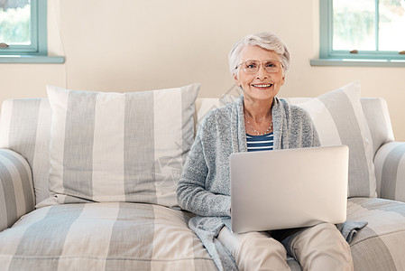我和日新月异的世界有联系 一位高龄妇女在家里沙发上用笔记本电脑图片