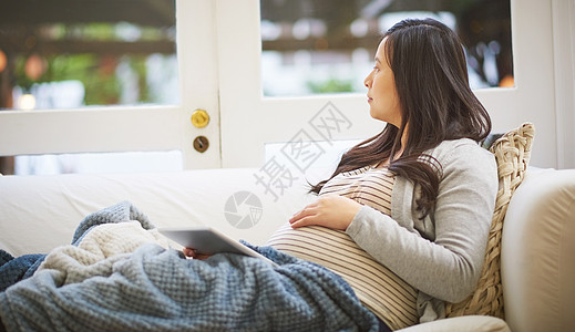 大日子就快到了 一个怀孕的孕妇 在家里用数码平板电脑的时候 看上去很体贴图片