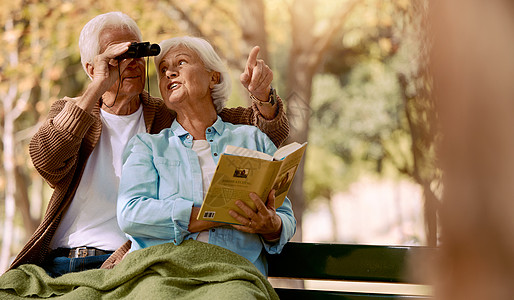 快乐的老年夫妇在公园里观鸟 在户外长椅上放松结合时间 自由和退休和平 老年婚姻爱情 双筒望远镜和男人指点的读书女人图片