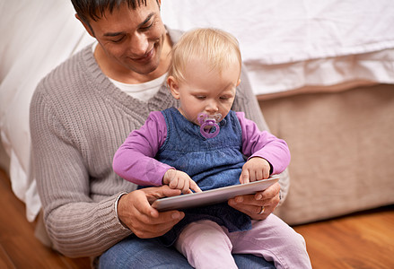 向爸爸展示它是如何完成的 一位年轻的父亲在数字平板电脑上给他的宝贝女儿看东西技术好奇心触摸屏婴儿孩子们金发药片童年孩子头发图片