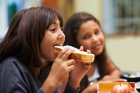 休息时享用三明治 午餐时间 一名年轻的女学生在自助餐厅吃三明治图片