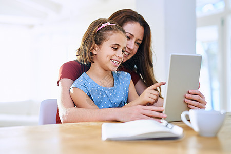 在数字时代学习 母亲和女儿在家里一起用数码平板电脑玩家的游戏图片