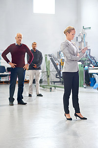 确保车间质量 一位经理在工厂检查期间与她的同事在后台使用平板电脑图片