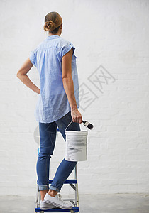 这可是个大任务 一个拿着油漆罐 站在梯子上的女人的后视镜头背景图片