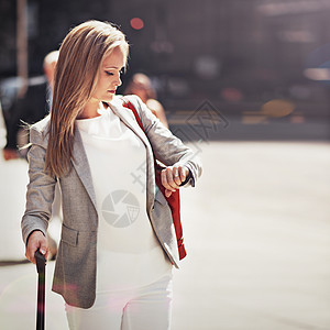 一位年轻女子在沿街行走时检查时间 她正在寻找时间图片