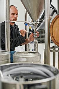监测从头到尾的酿造过程 一个在微酿酒厂工作的男人图片