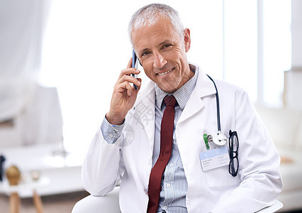 你的健康是我第一要务 一位成熟医生的肖像 用手机坐在他办公室里 用手机图片