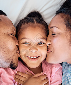 一个黑人家庭的父母亲吻 女儿和微笑肖像 以及爱 纽带和关怀 孩子的家 幸福和青春 母亲和父亲俯视脸颊 在卧室床上亲吻脸图片