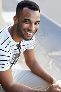 给你他最灿烂的笑容 一位穿着随意的英俊非洲裔美国商务人士坐在城市里喝咖啡图片