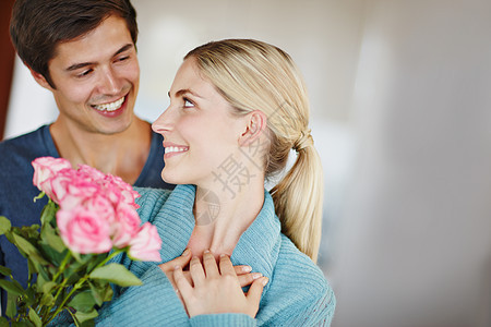 他们的爱情正在绽放 一个深情的年轻人给他美丽的年轻妻子一束粉红玫瑰图片