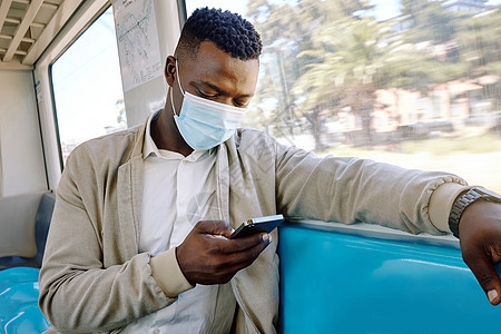 独自旅行的黑人商务人士 一位年轻的非洲裔美国商务人士在去城里的火车上坐在窗边玩手机面具成人商业工人工作男人电话管理人员男性城市图片